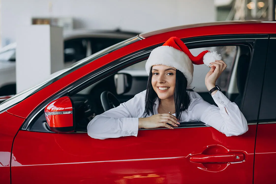 Dievča v aute so Santa čiapkou, symbolizujúce sviatočnú vianočnú ponuku vodičského kurzu v Trnave